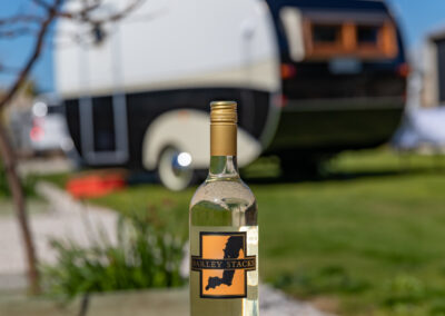 A bottle of Barley Stacks Wines' Viognier on a log with the MBC Foods Food Van in the background.